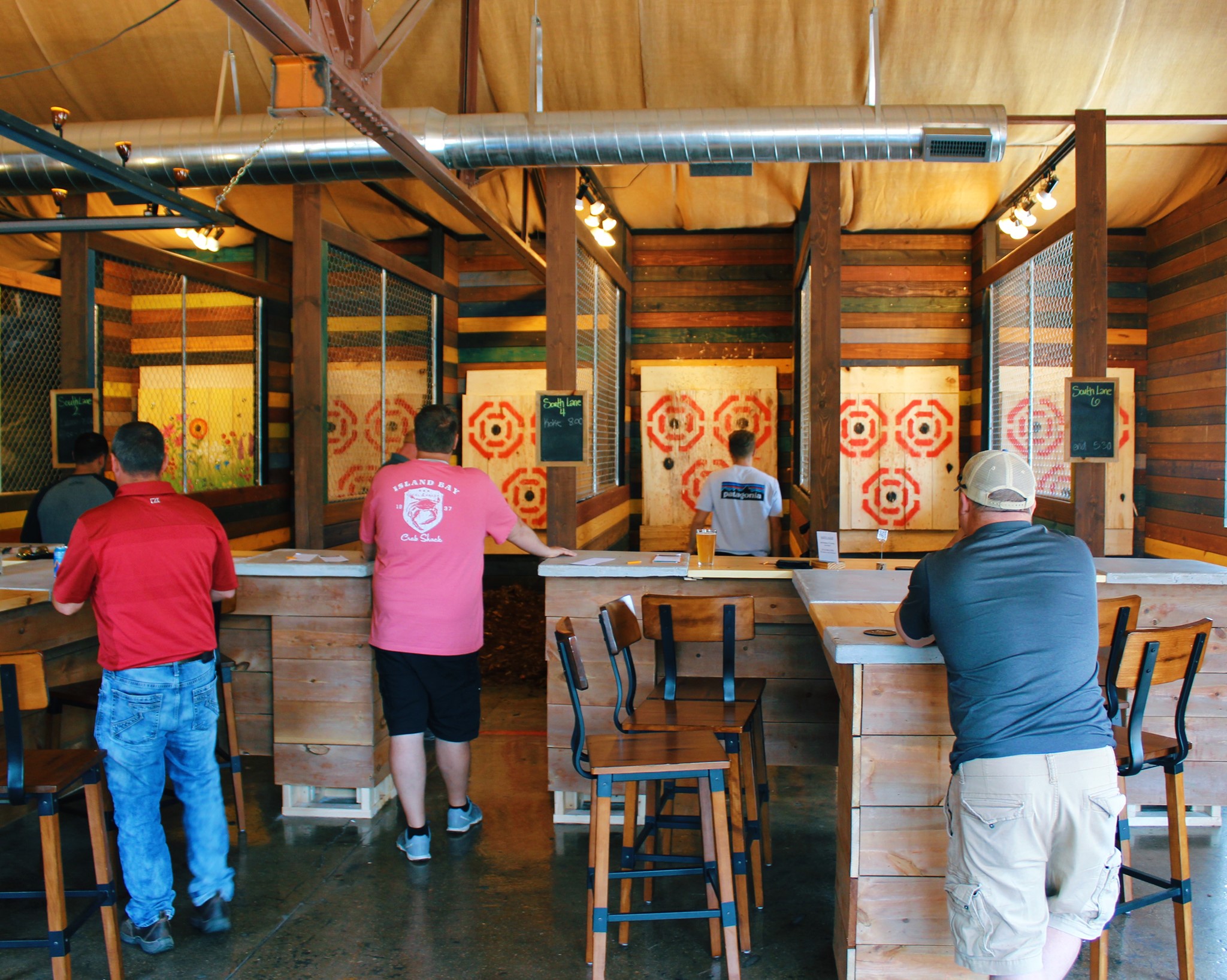 People at different axe throwing stations